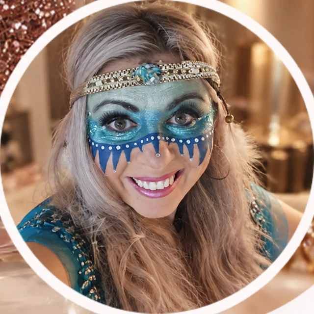 De beheerder van GLOW met turquoise en blauwe schmink en een zilverkleurige hoofdband.
